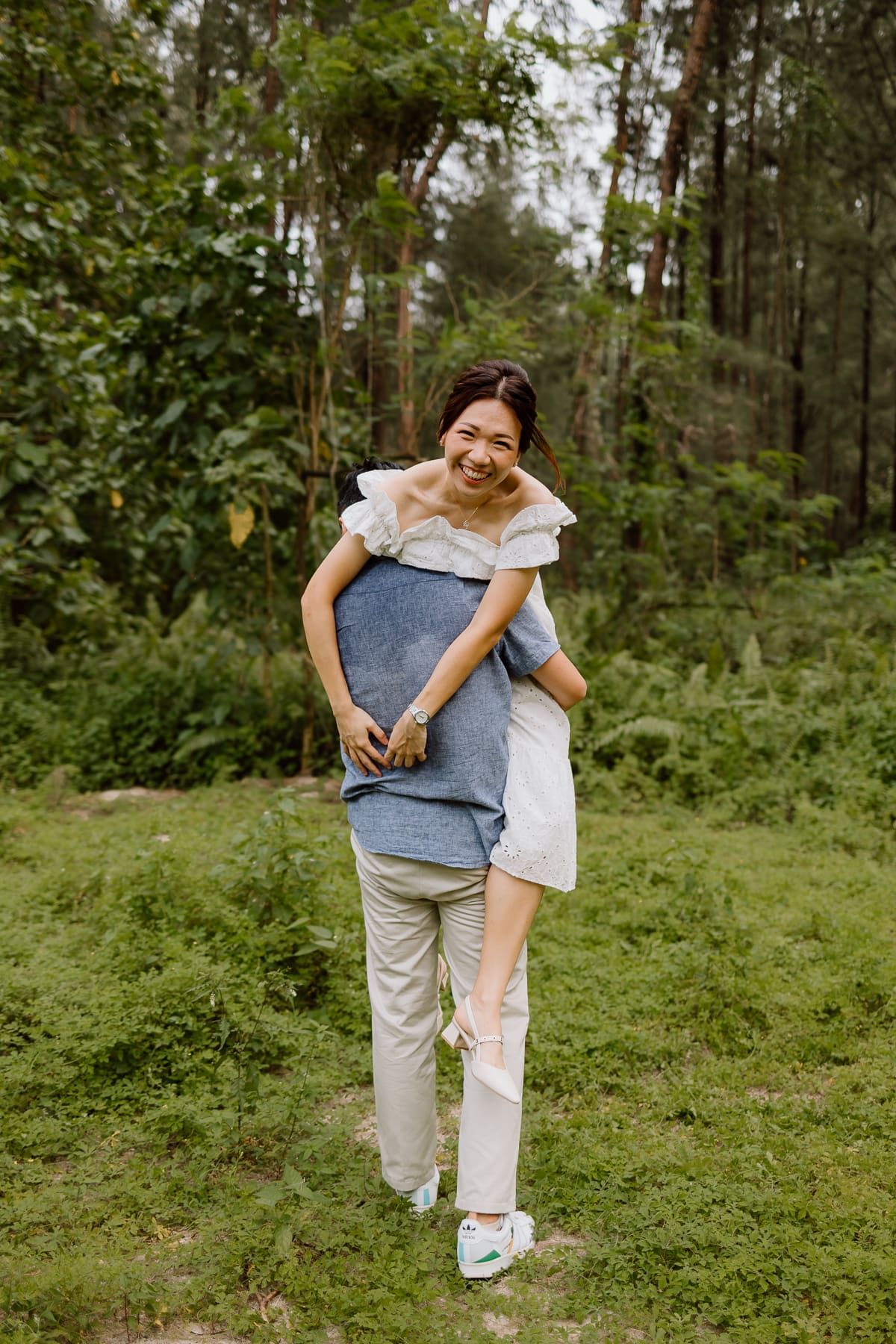 Playful moment of carrying each other in a lush forest setting.