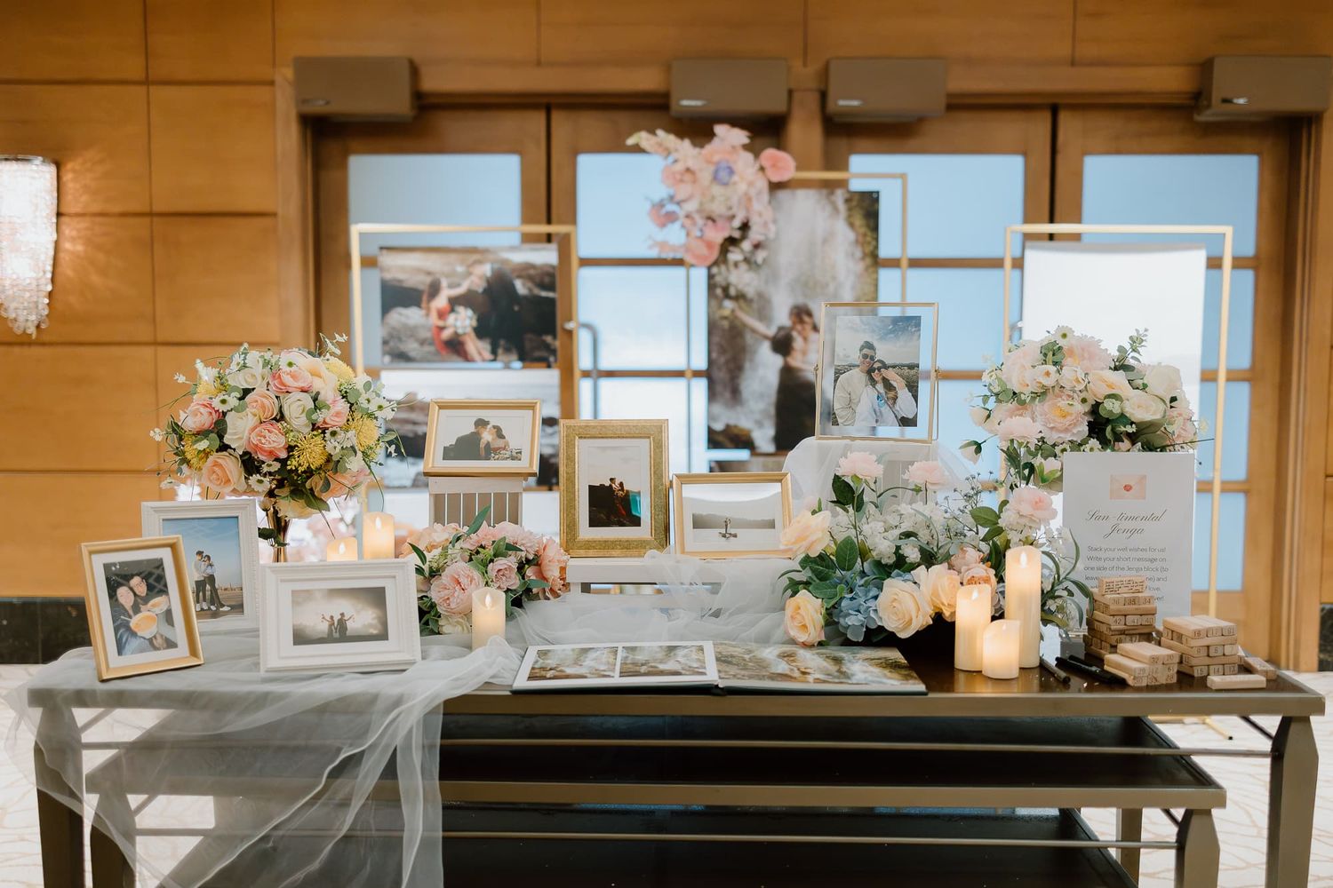Wedding reception venue with display tables featuring photo frames and floral decorations.