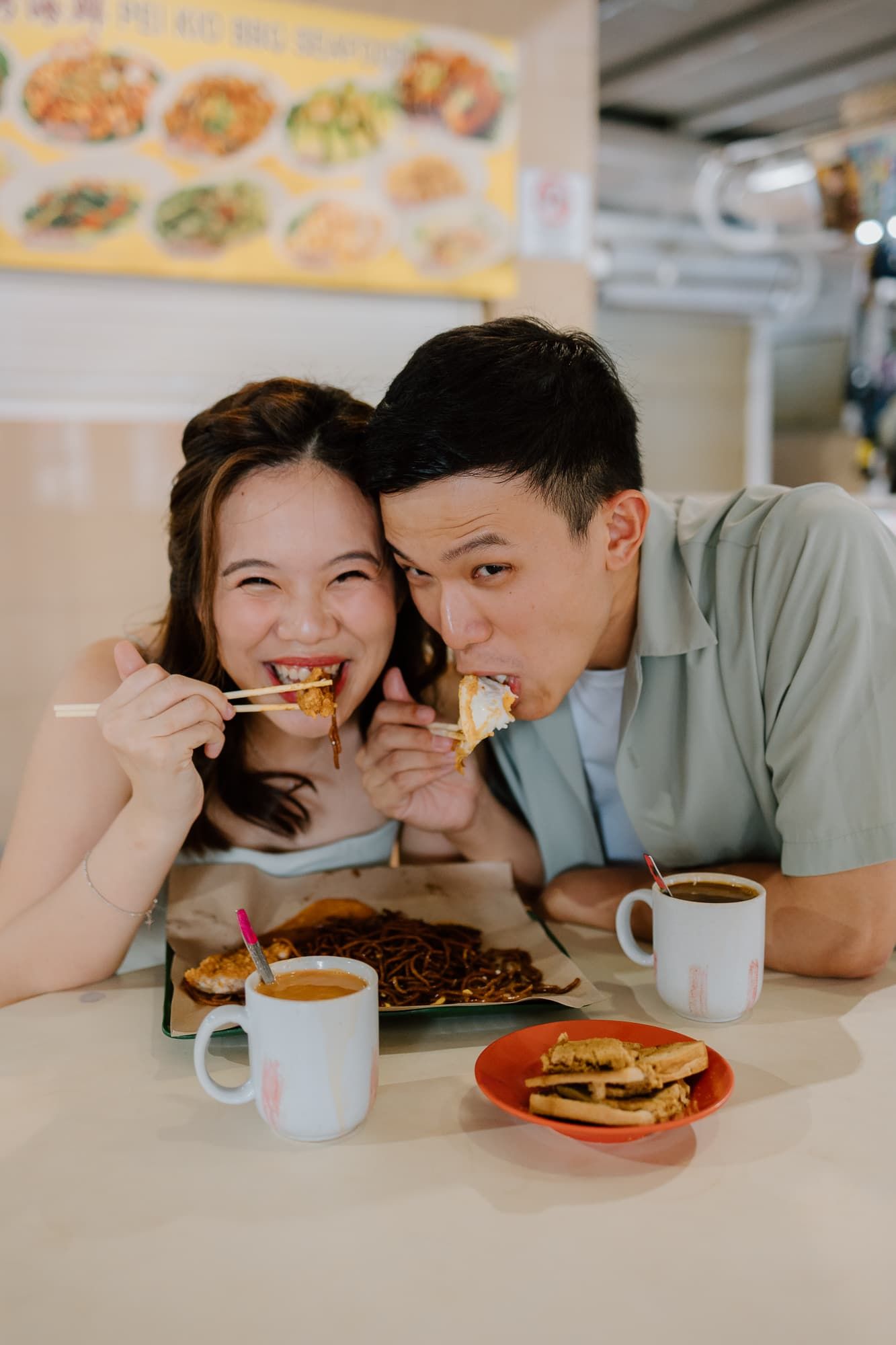 A couple feeding each other food while dining at a casual restaurant.
