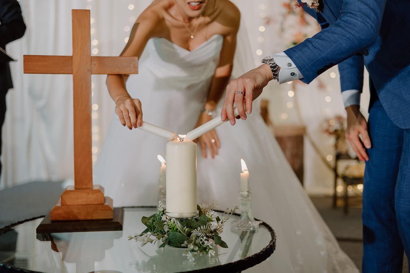 A unity candle ceremony moment with a wooden cross and white candles.