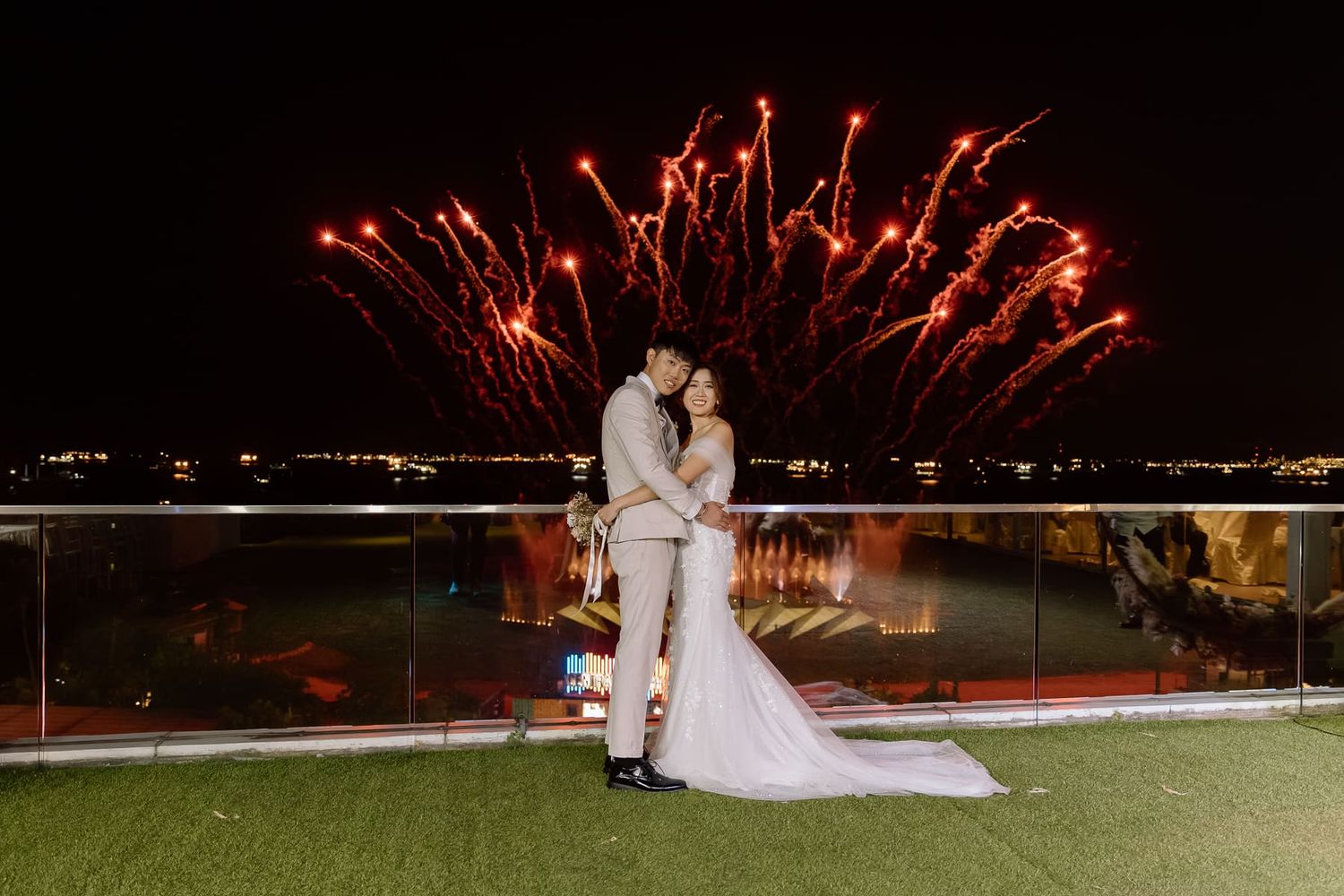 Nighttime wedding celebration with fireworks display over dark landscape.