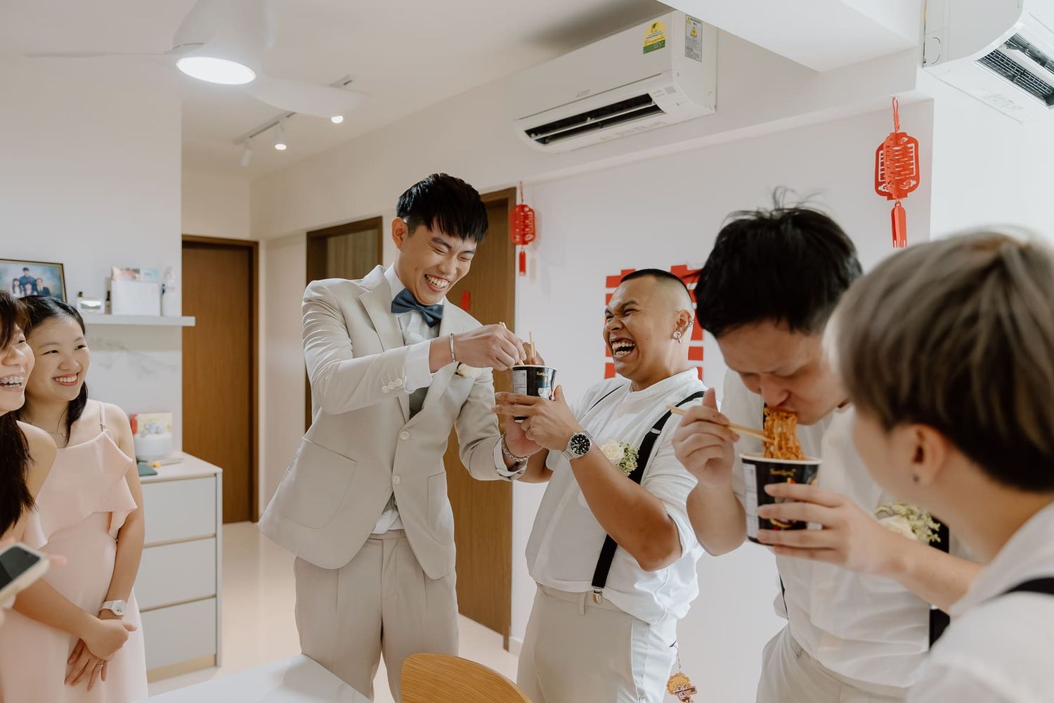 Groomsmen in white attire laughing and joking together during wedding preparations.