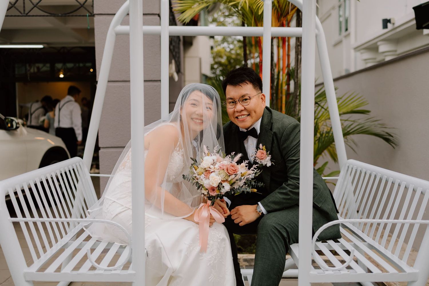 A couple shares a sweet moment together while seated on a white wooden porch swing.