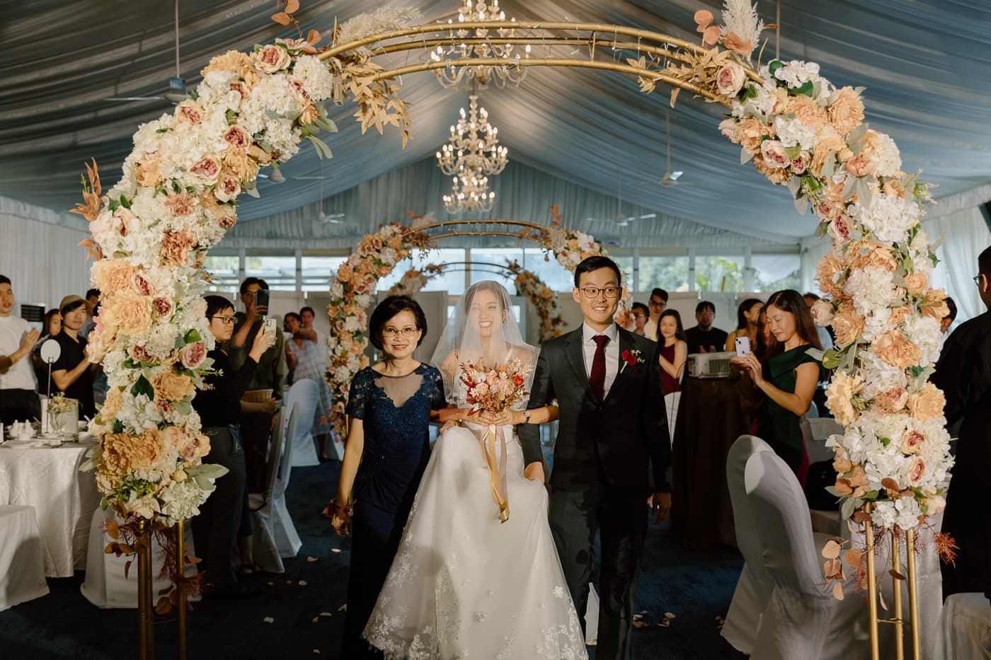 Wedding ceremony in a elegant venue with floral arch decorations and chandeliers.