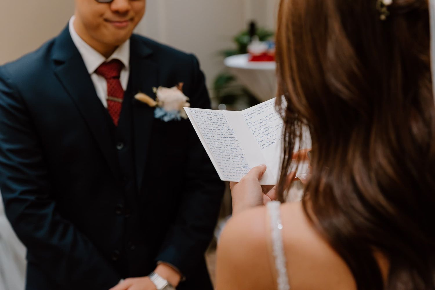 Close-up of couple exchanging written vows during intimate indoor wedding ceremony.
