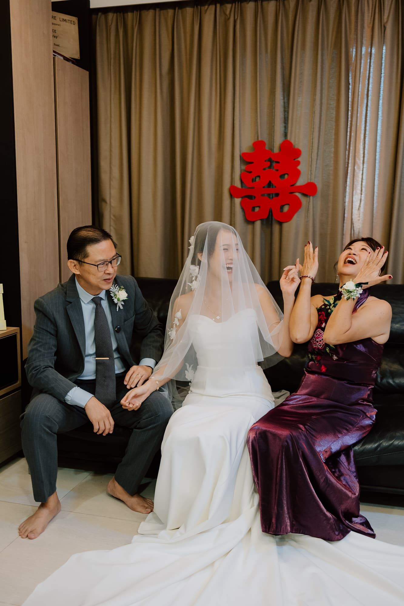 A candid wedding moment with traditional Chinese double happiness symbol hanging in the background.