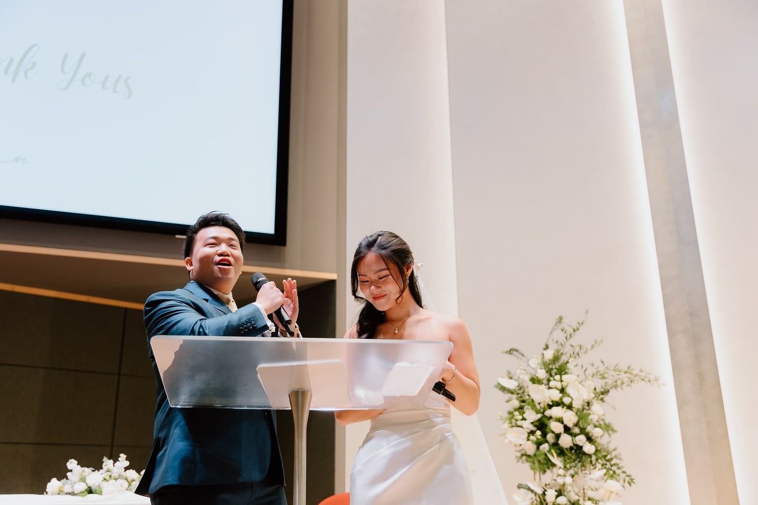 Wedding ceremony scene with white decor and floral arrangements in an elegant indoor venue.