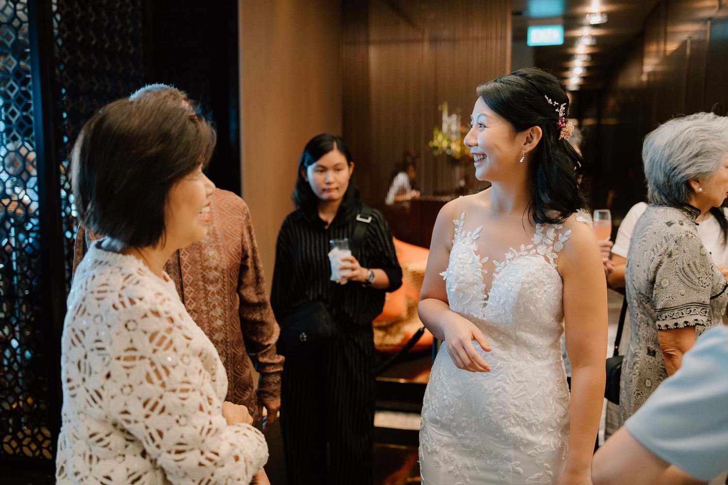 People celebrate at a wedding reception with guests seated at round tables for dinner and socializing.