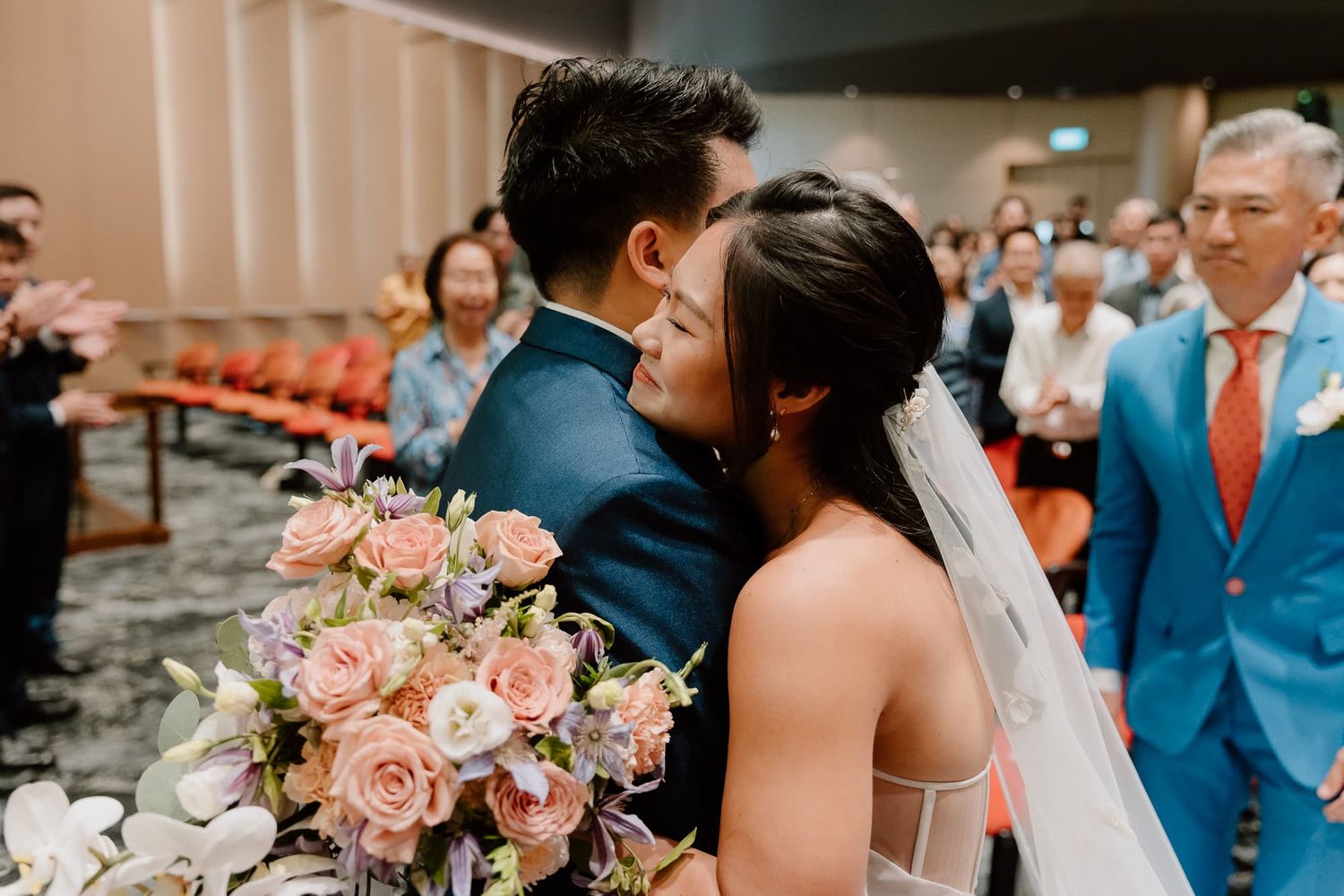 Elegant wedding ceremony with pink floral arrangements and guests in formal attire.