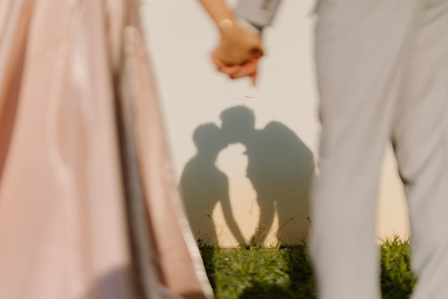 Creative shadow silhouette of a romantic couple against grass during golden hour.