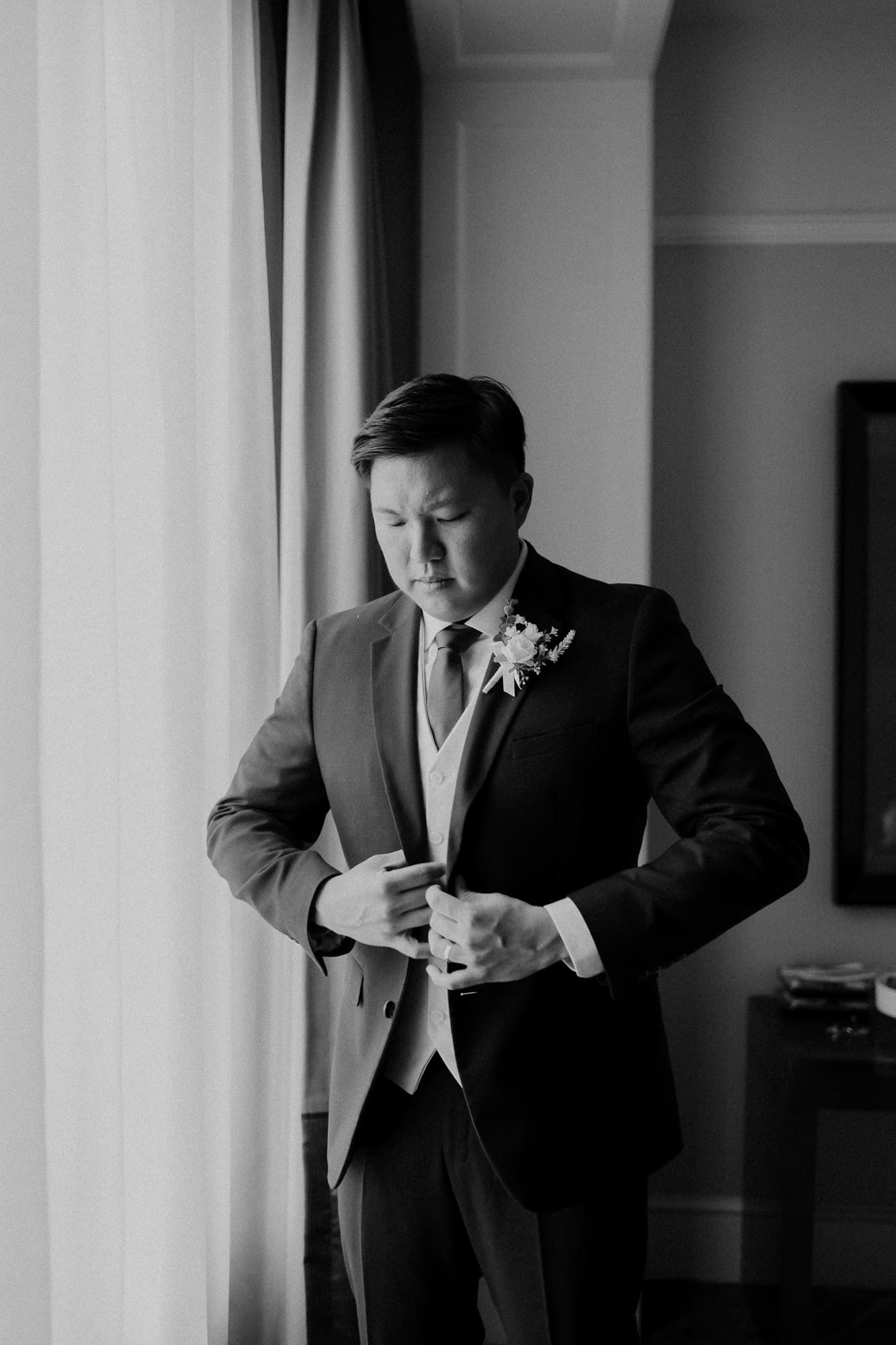 Black and white photos of groom adjusting his suit and tie before the ceremony.