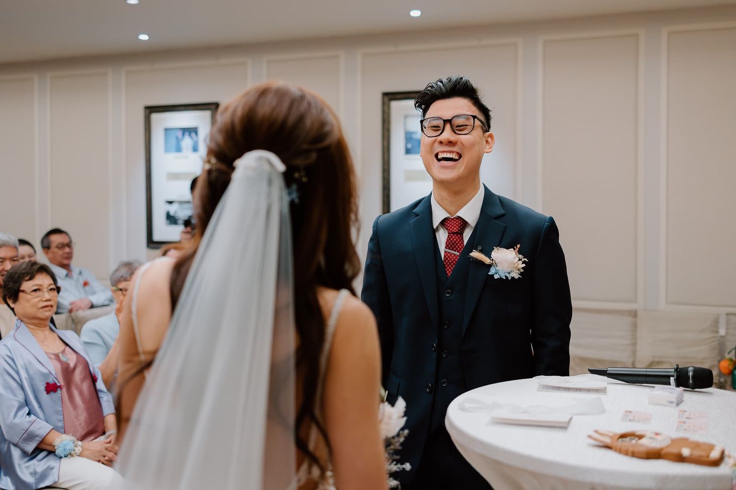 Joyful couple sharing a laughter-filled moment during an intimate wedding ceremony in an elegant indoor venue.