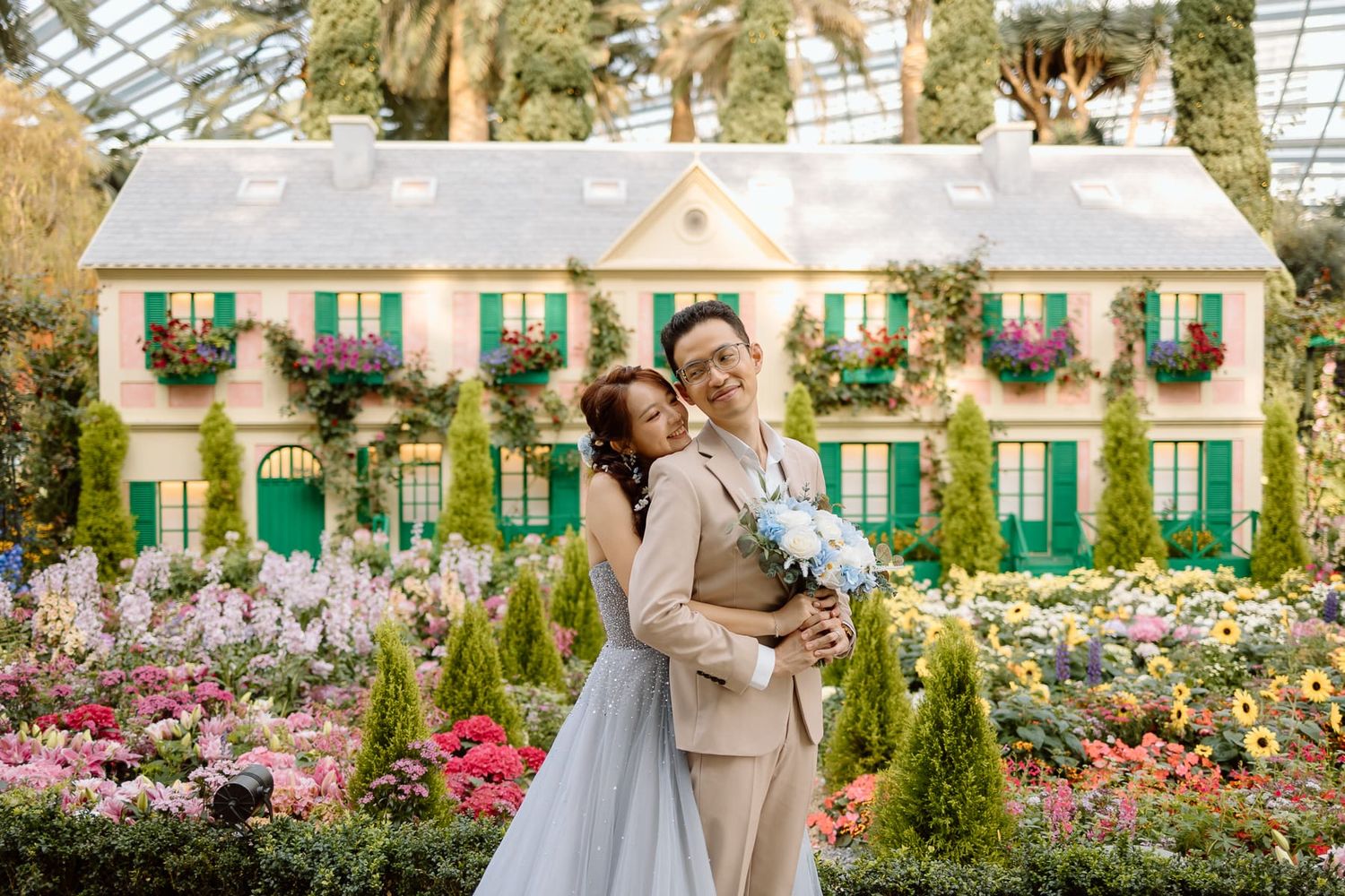 A romantic garden wedding photoshoot in front of a charming cottage adorned with floral window boxes and green shutters.