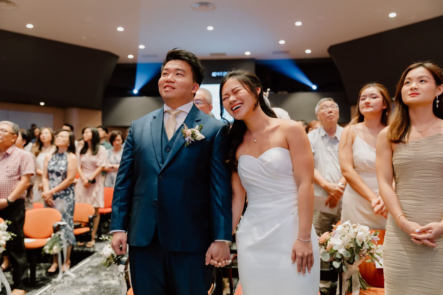 Panoramic view of a modern indoor wedding ceremony with guests seated in rows.