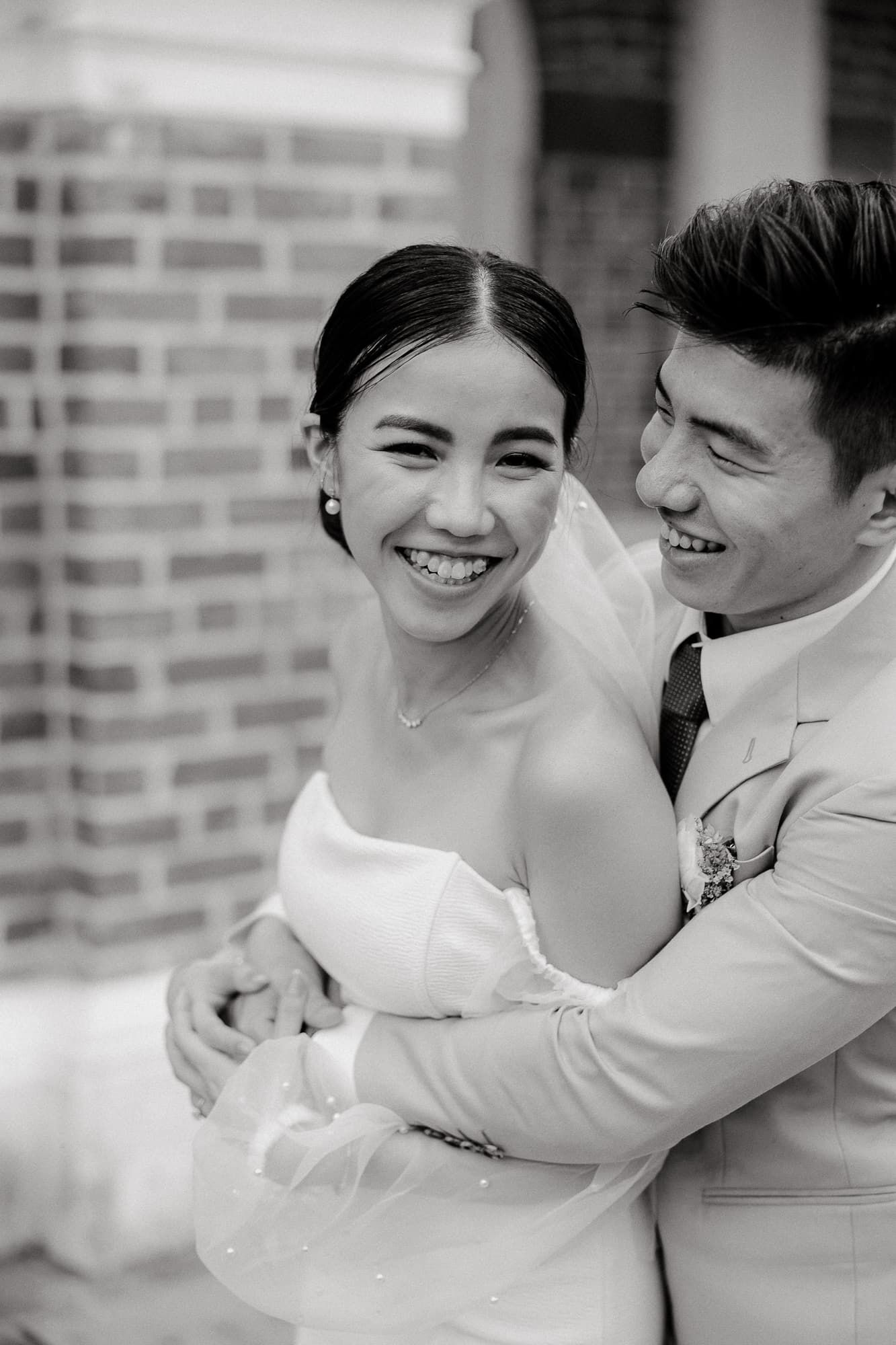 Black and white candid wedding portrait showing a joyful embrace.