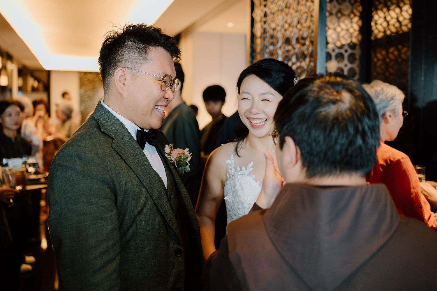 Guests celebrate and mingle at an elegant indoor wedding reception venue with warm lighting and decorative details.