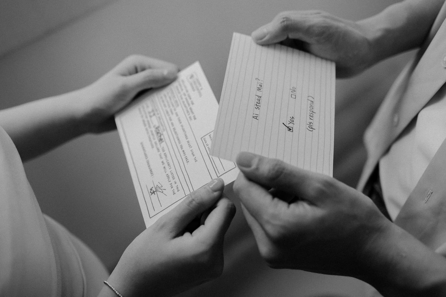 Two pairs of hands exchanging official documents in black and white.