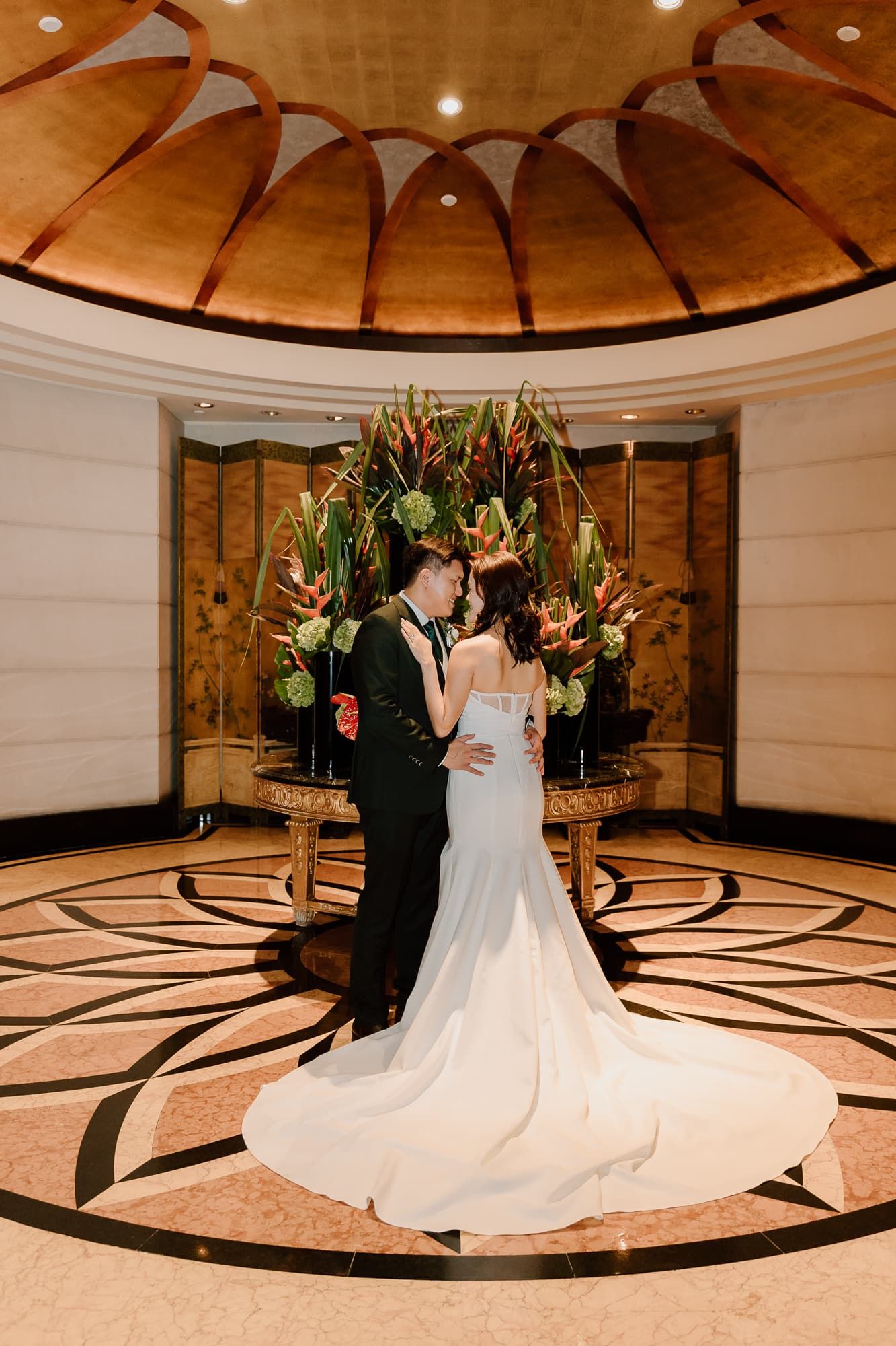Wedding dance captured on ornate circular floor pattern under domed ceiling with dramatic lighting.