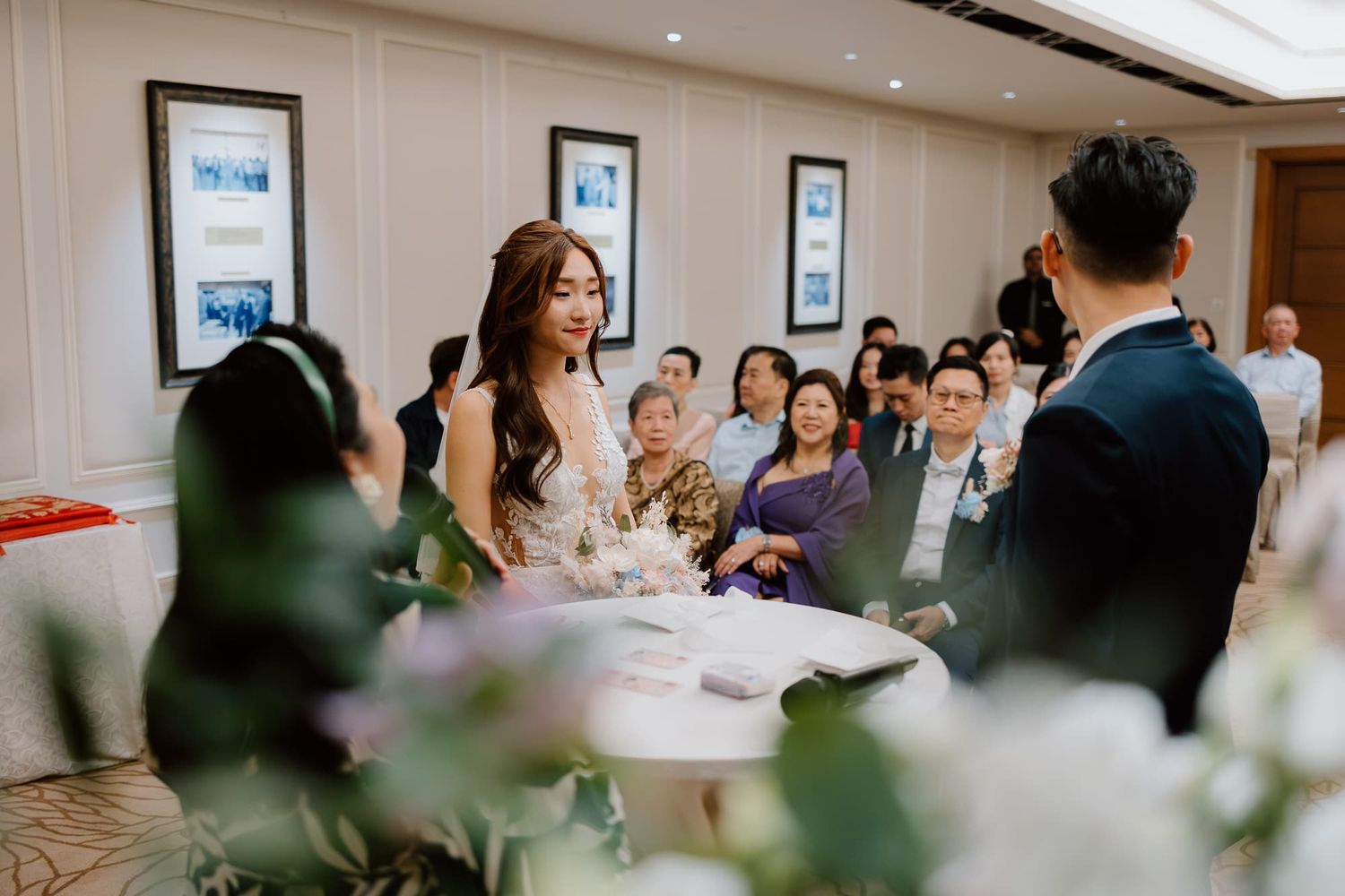 Beautiful wedding ceremony scene with floral decorations and guests watching the couple's special moment.