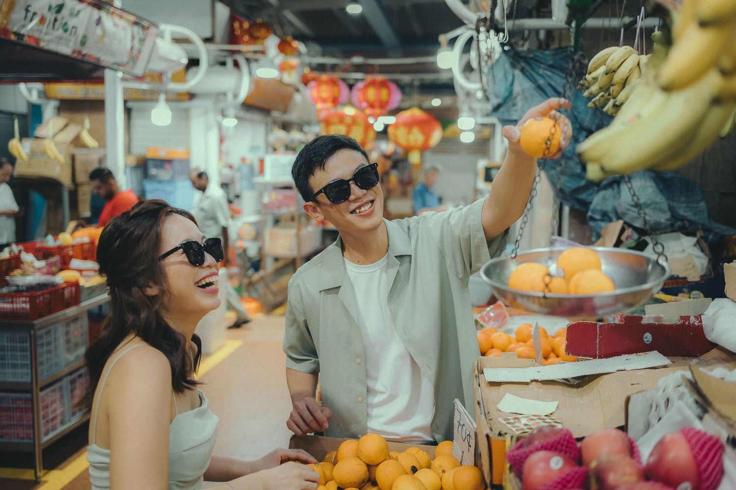 A couple shopping at a vibrant fruit market with colorful produce displays.