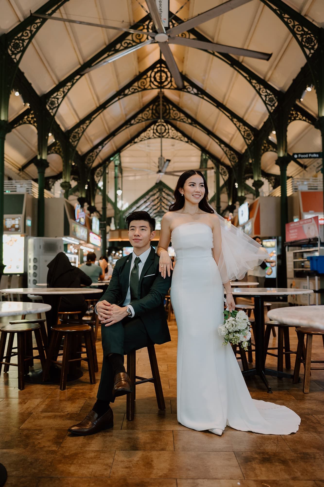 Wedding couple poses playfully in a rustic indoor venue with ornate ceiling details.