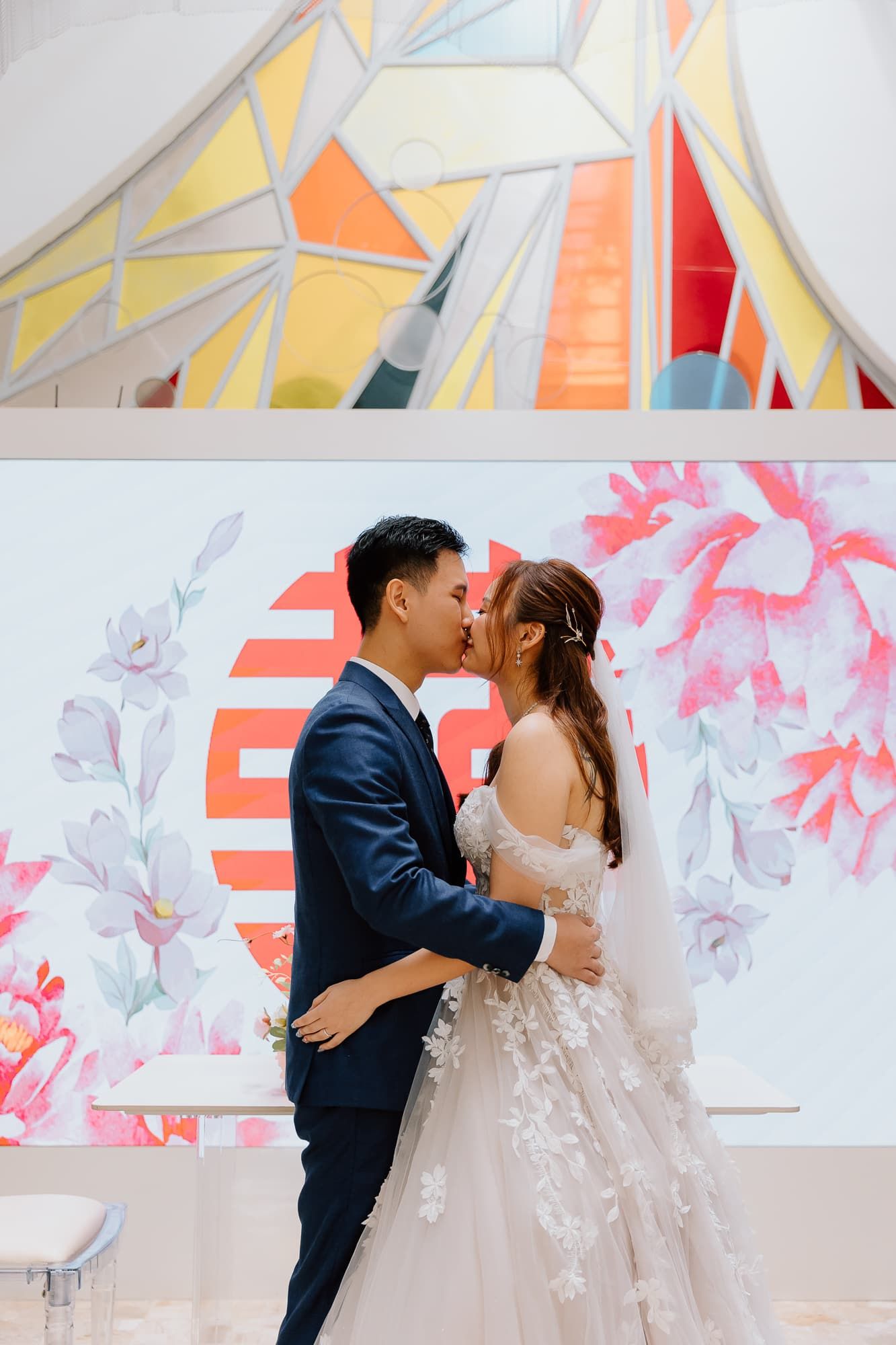 Traditional wedding ceremony with couple in formal attire against floral backdrop.