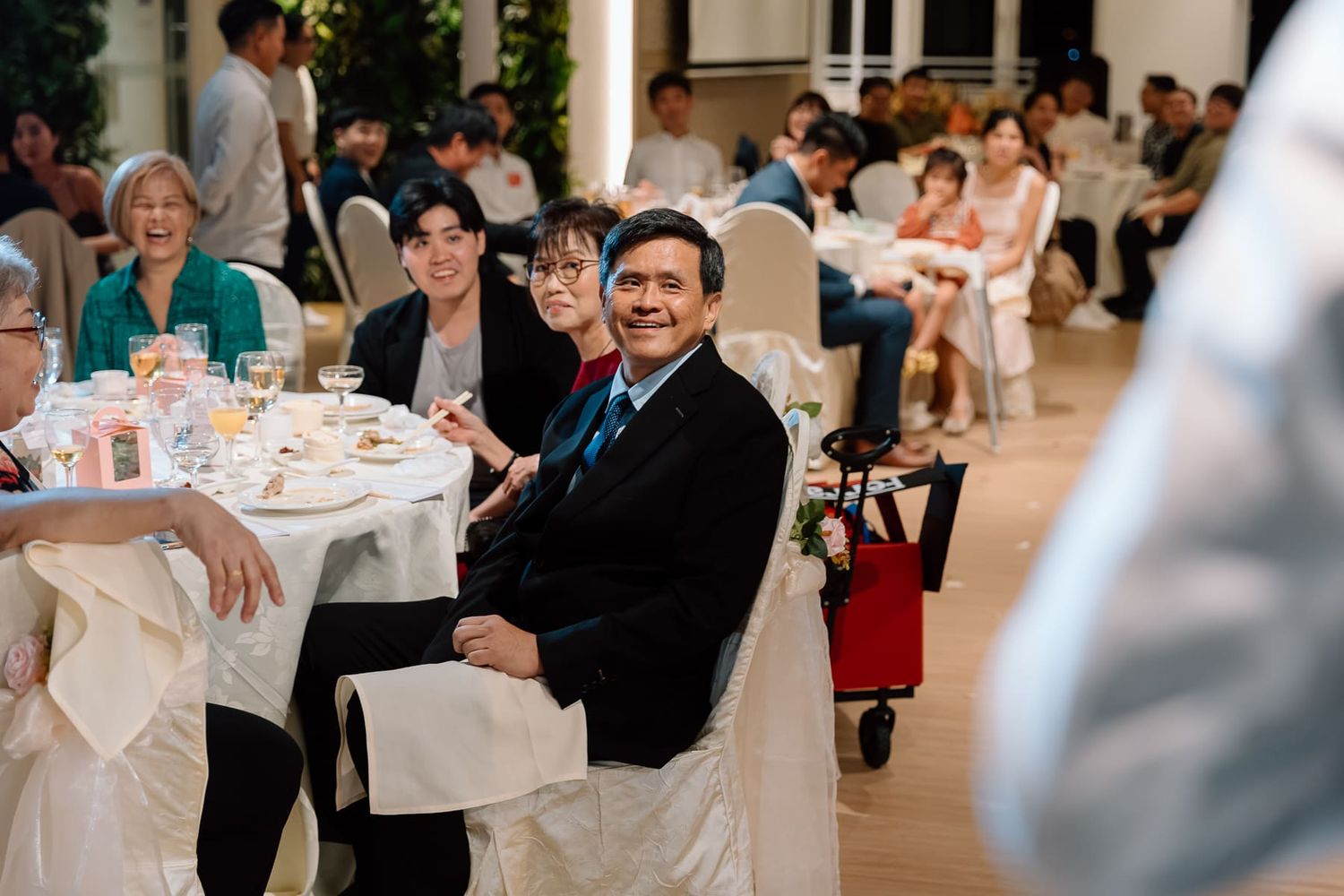Wedding guests seated at elegant white-clothed tables during a reception celebration.