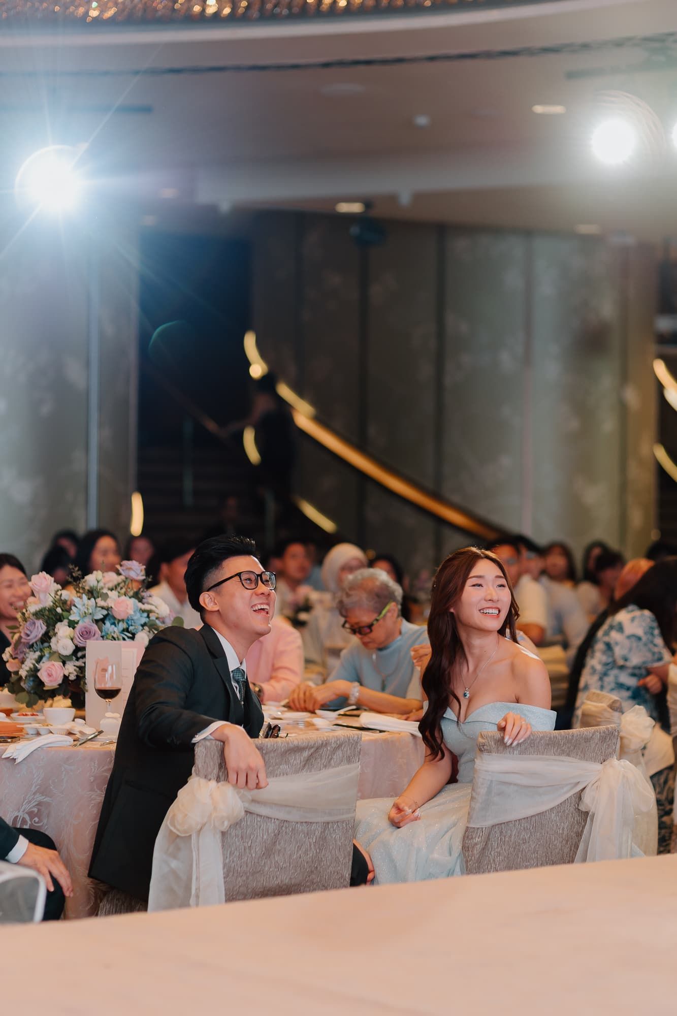 Wedding guests laughing and enjoying themselves at elegantly decorated reception tables with white chair covers.