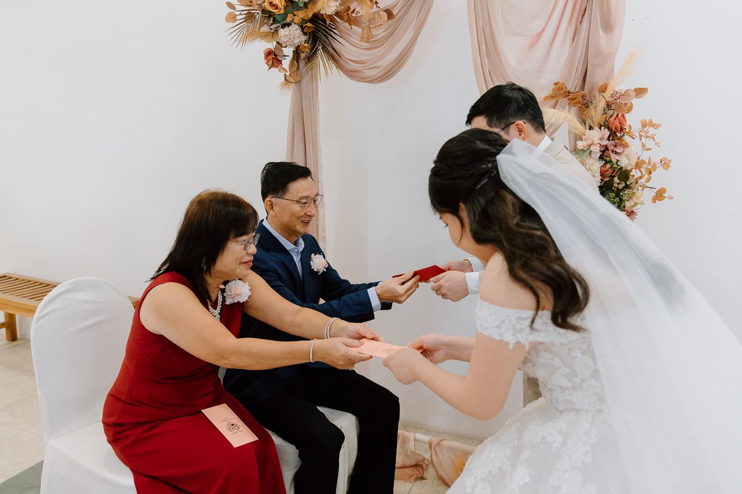 A traditional wedding ceremony moment in front of floral decorations.