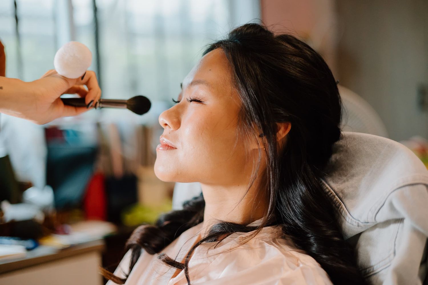 Close-up of someone getting makeup applied during wedding preparation.