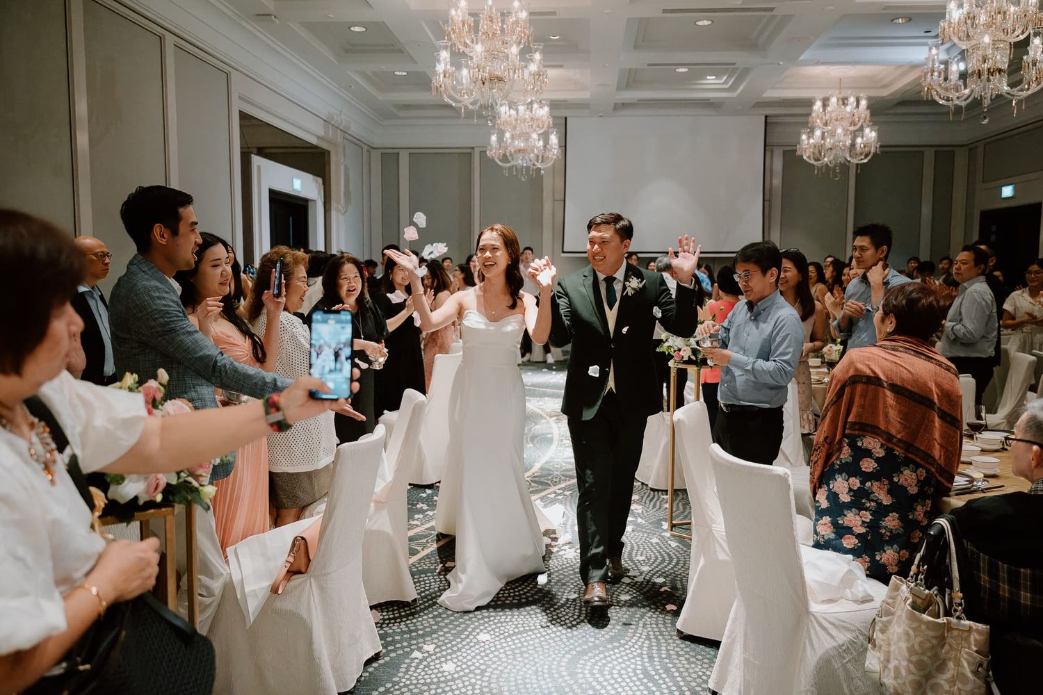 Wedding reception dance floor filled with celebrating guests under crystal chandeliers.
