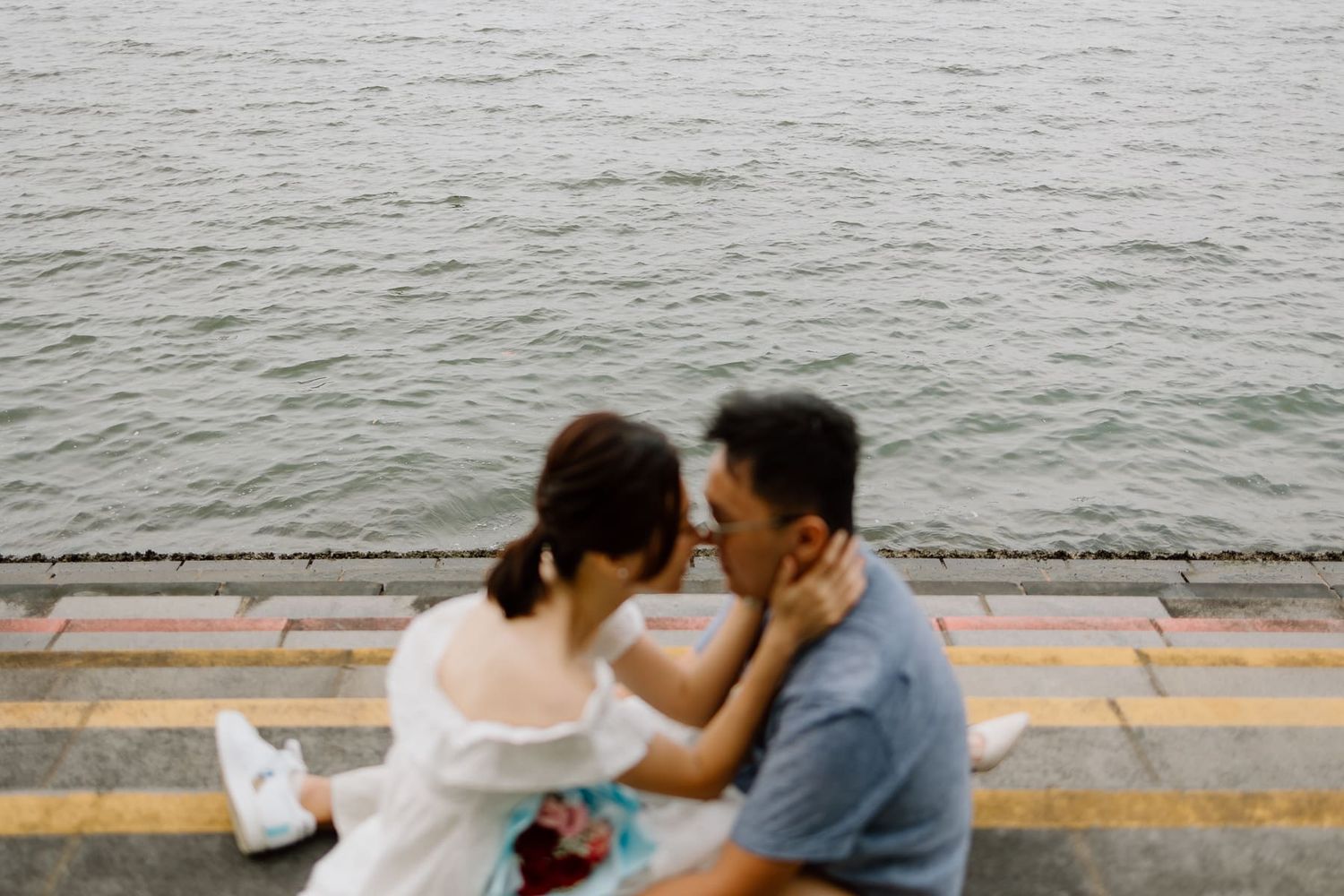 A tender moment between a couple sitting by the waterfront.