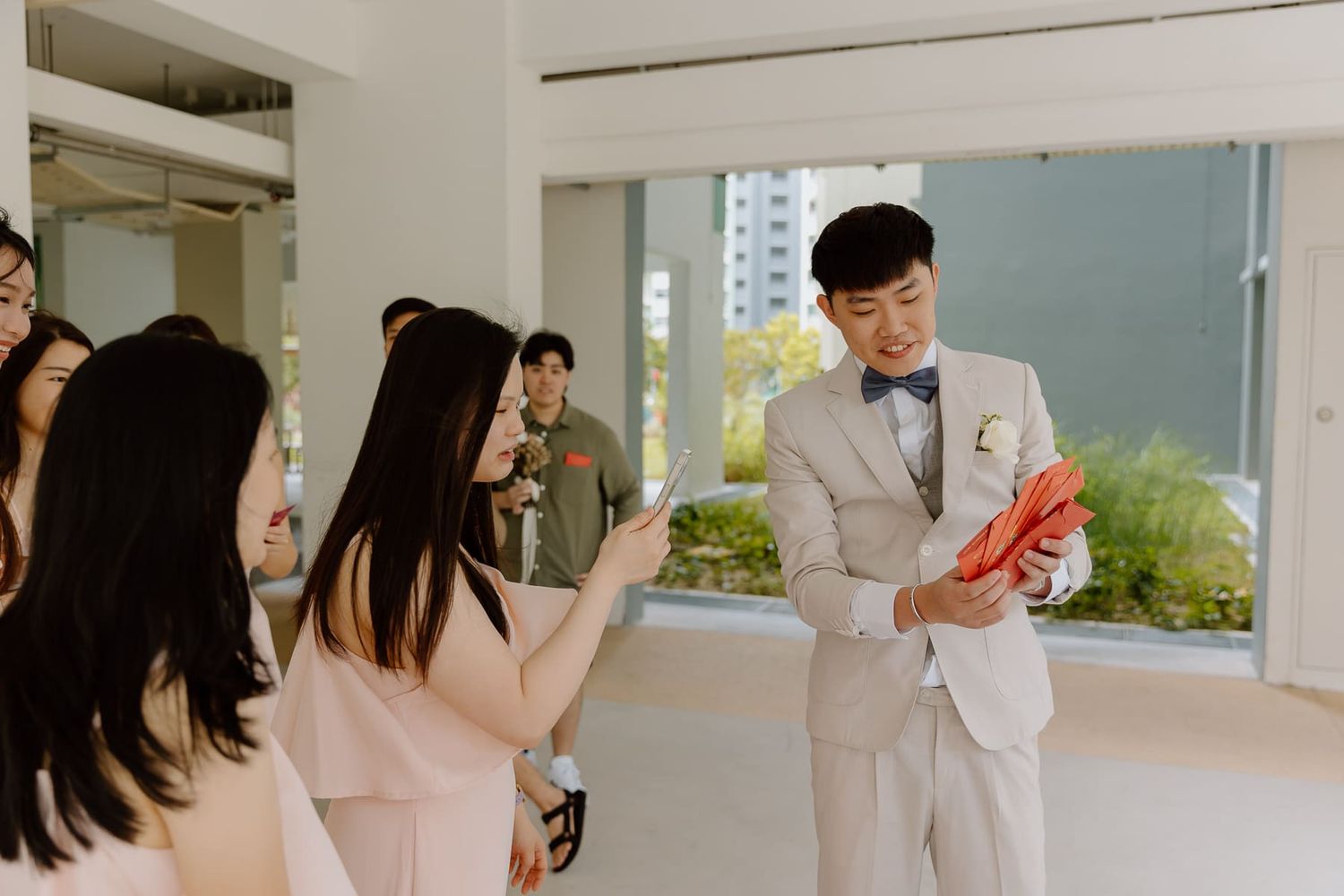 Wedding party members share laughs and candid interactions in a bright indoor space.
