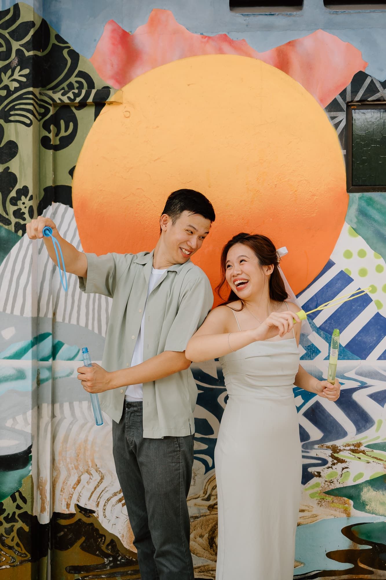 Couple dancing and laughing in front of colorful mural with large orange circle.