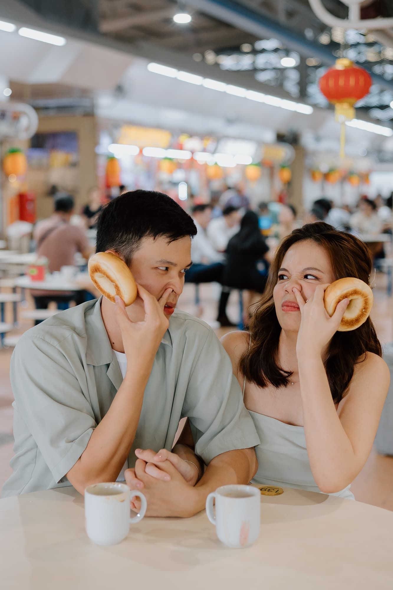 A couple shares a tender moment in an Asian food market setting.