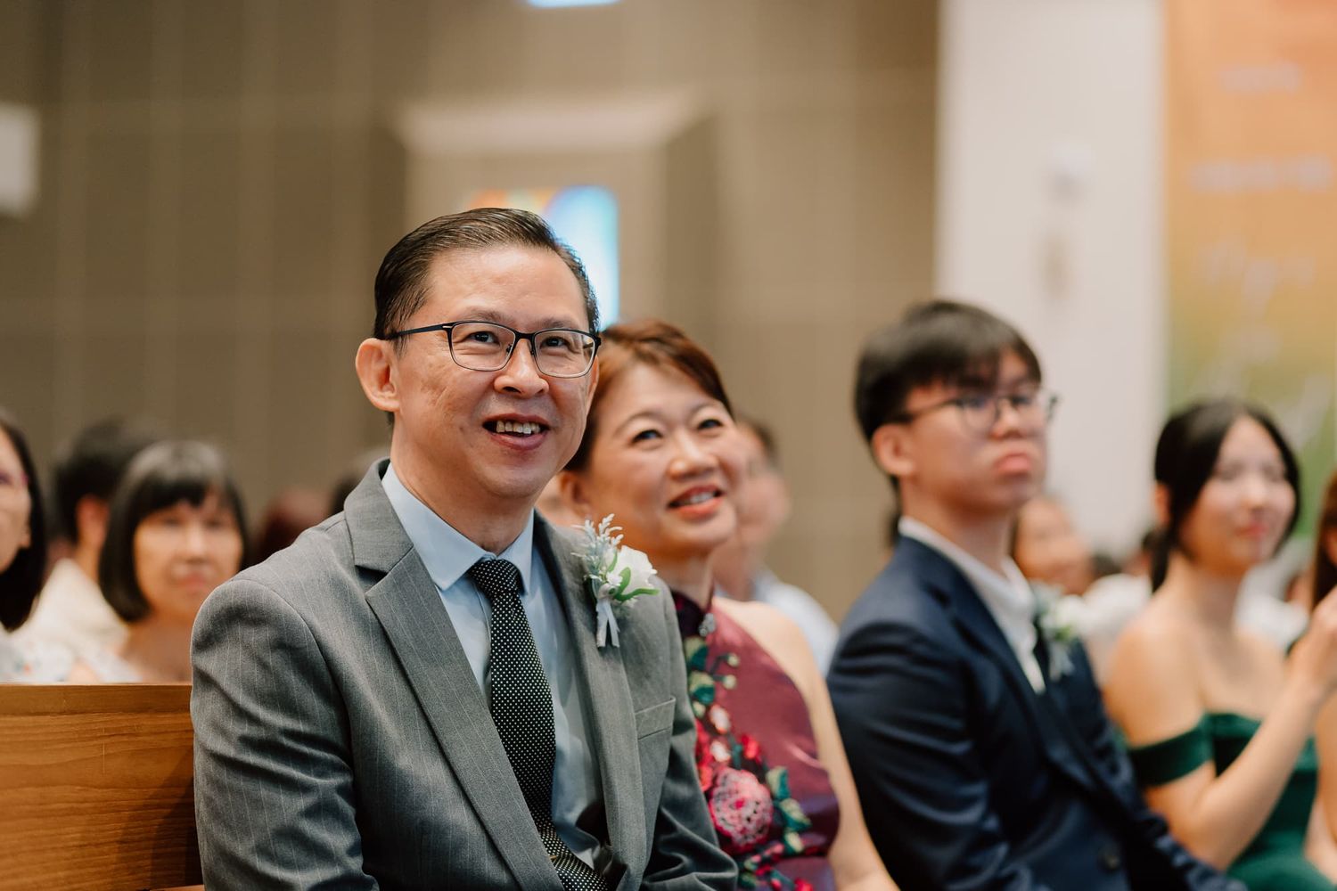 Church wedding ceremony guests seated in pews enjoying light-hearted moments.