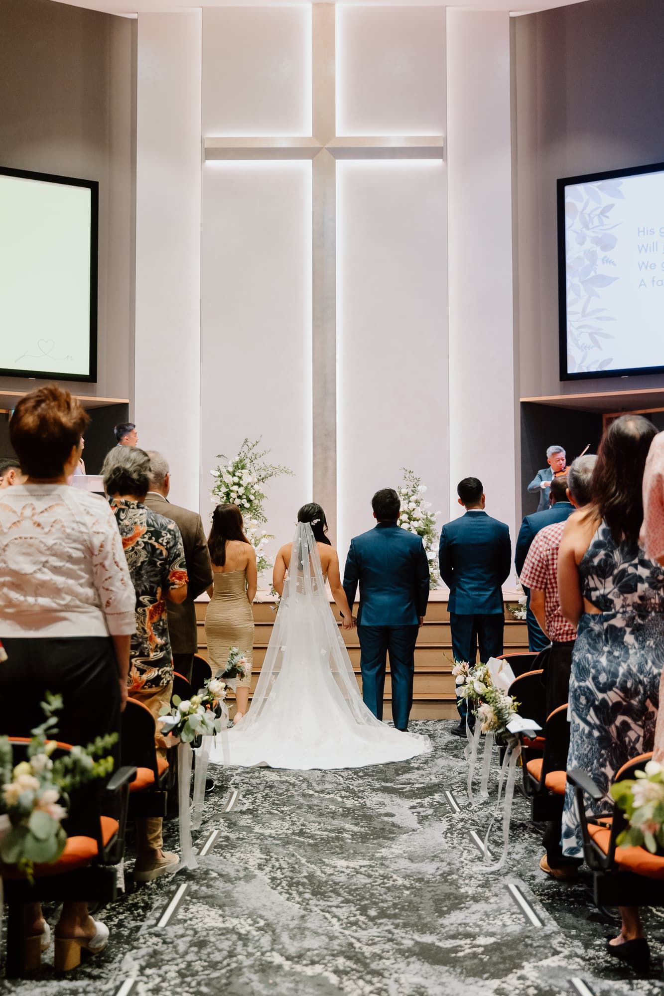 Wedding ceremony in a modern church with white walls and cross windows.