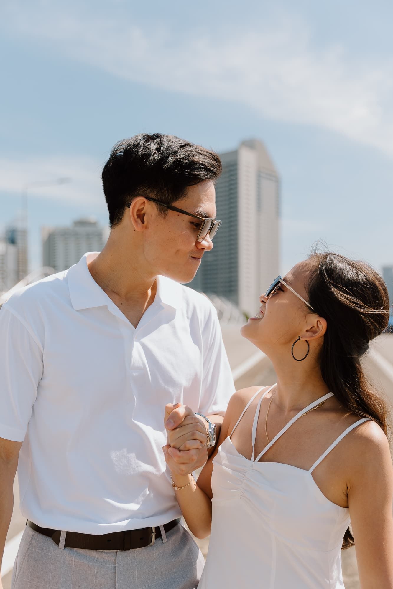 Couple in white attire sharing an intimate moment against a city backdrop.