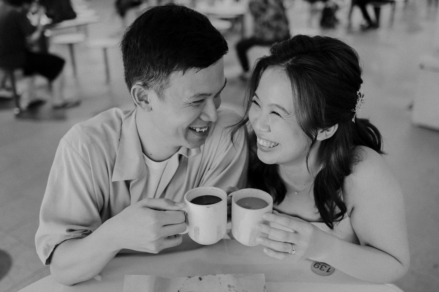 A couple laughing while drinking coffee at a casual dining spot.