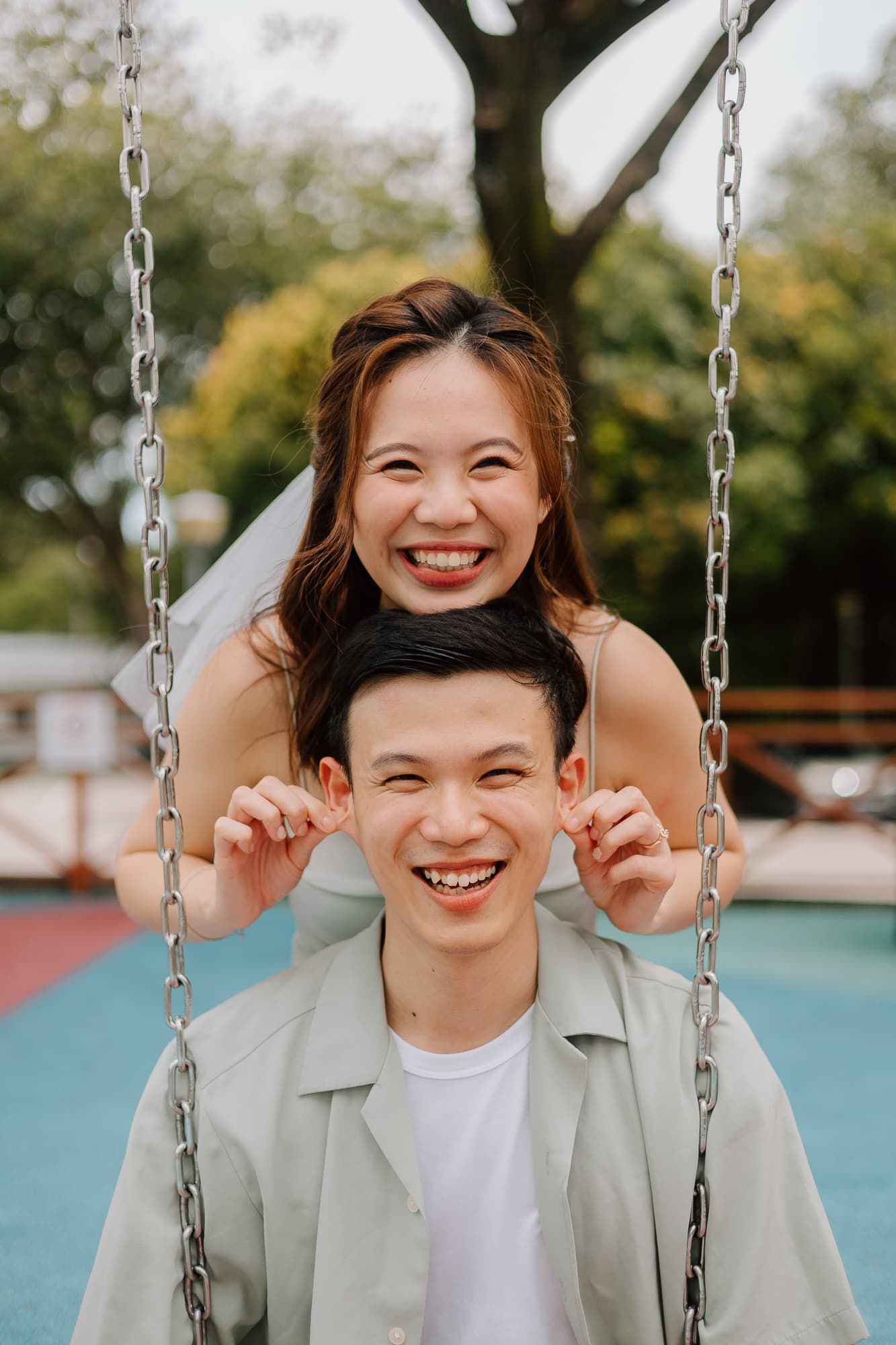 Joyful moment shared between two people on a playground swing set.