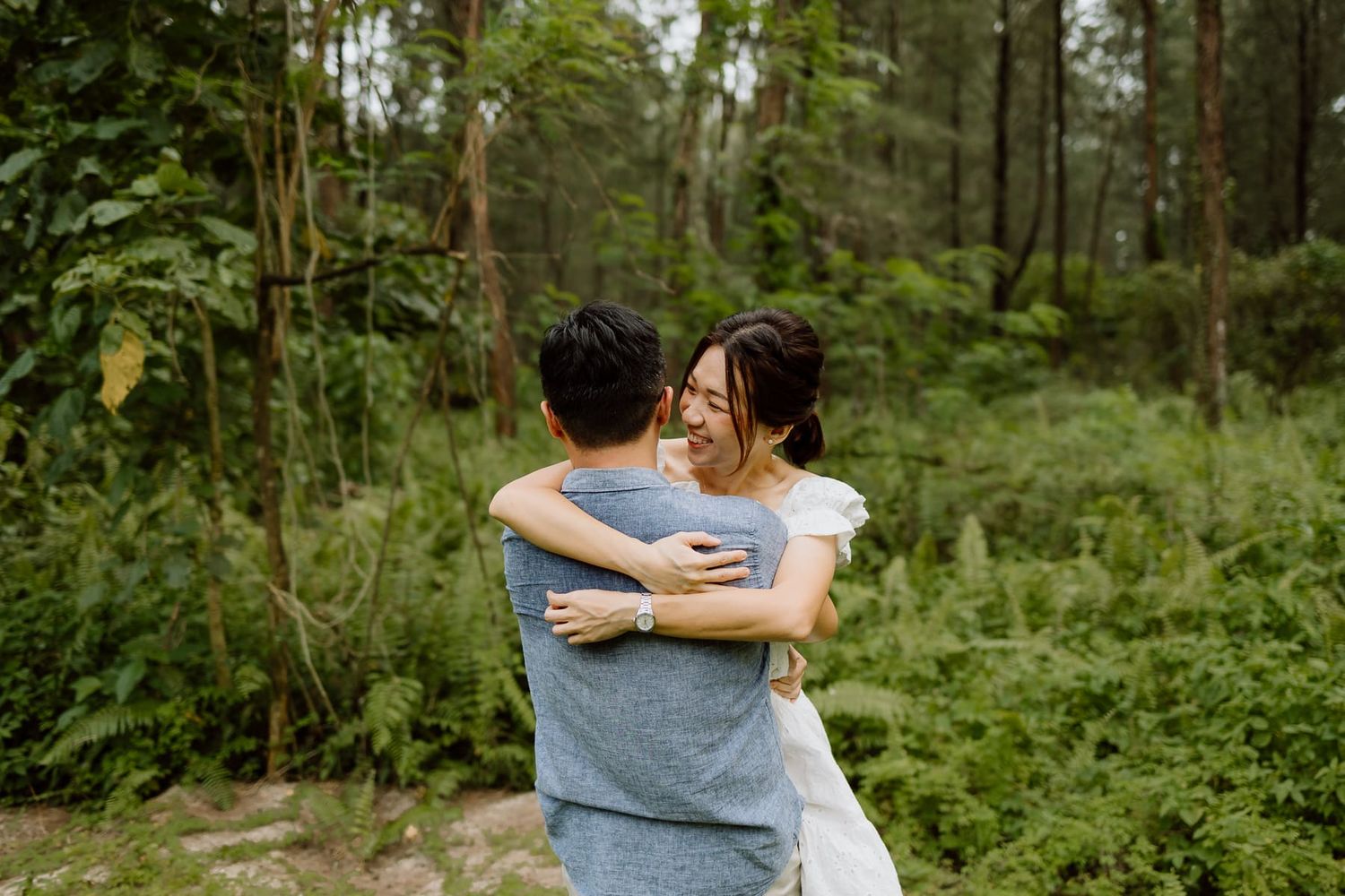 Intimate embrace captured in a verdant forest setting.