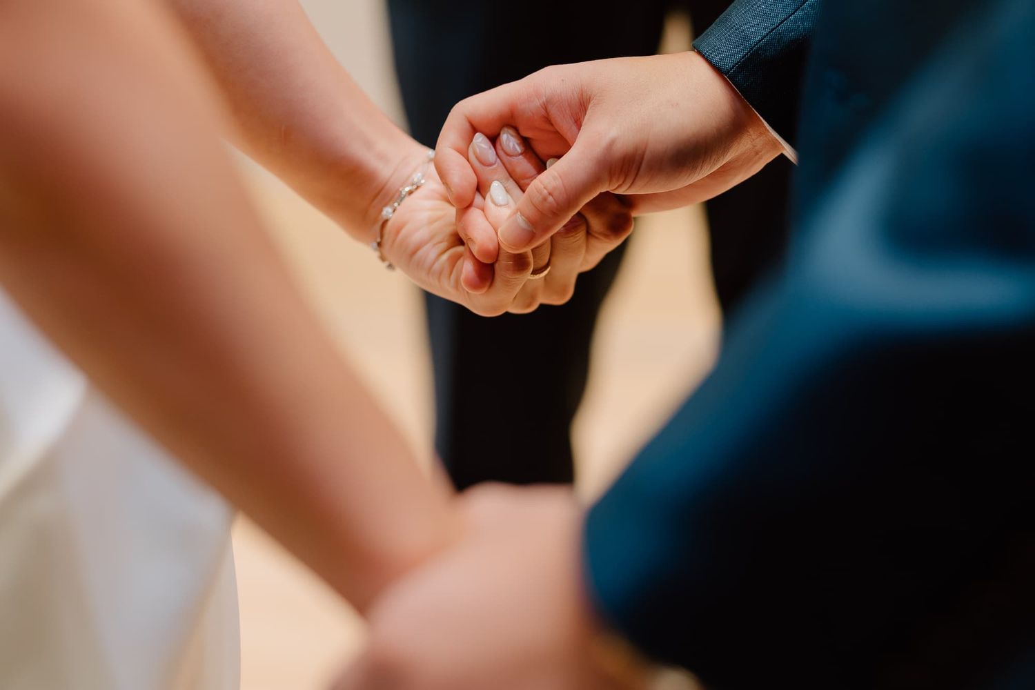Close-up shot of hands during an intimate wedding ceremony moment.