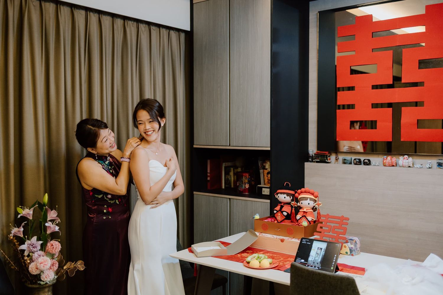 A wedding preparation scene with traditional Chinese double happiness character and decor in the background.