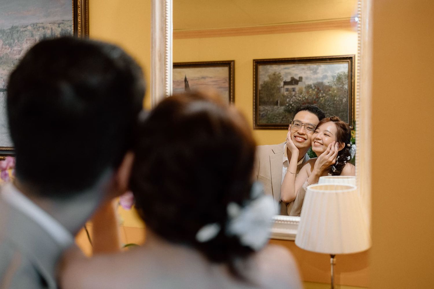 A reflection captured in a mirror showing a tender moment during wedding preparations.