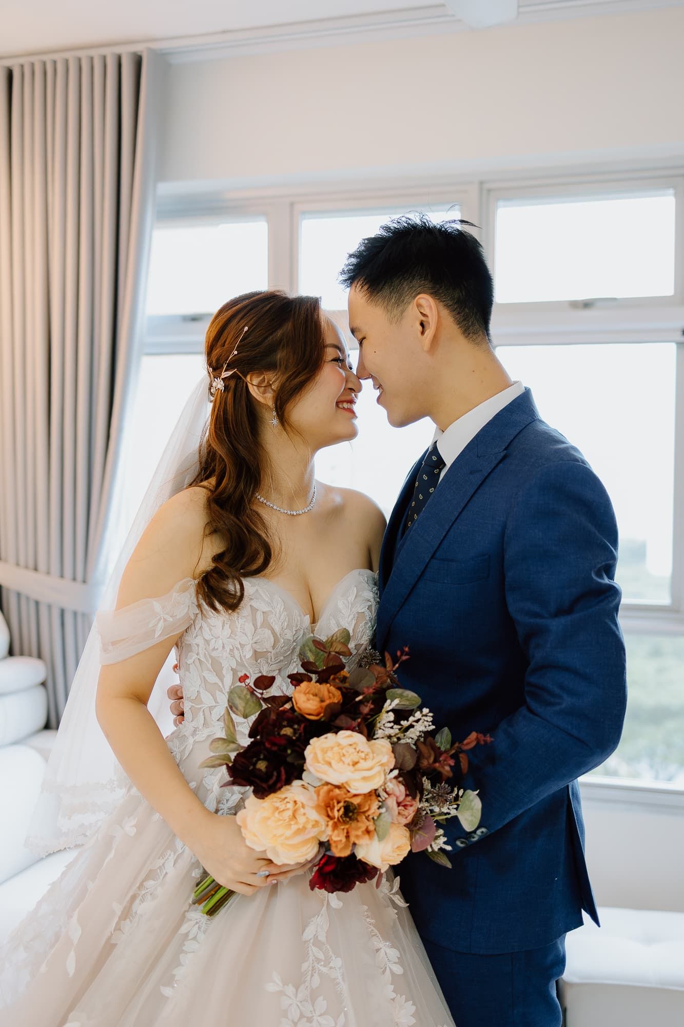 Intimate moment between couple with beautiful peach and burgundy bouquet in bright room.