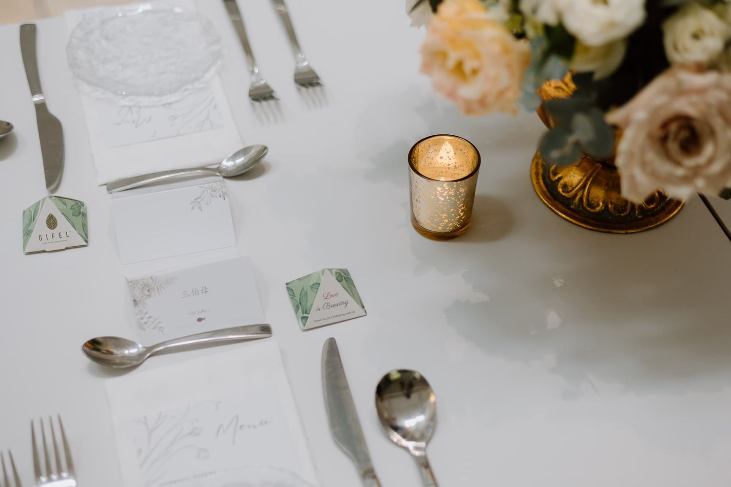 Elegant wedding table setting with white linens, silverware, and glassware.
