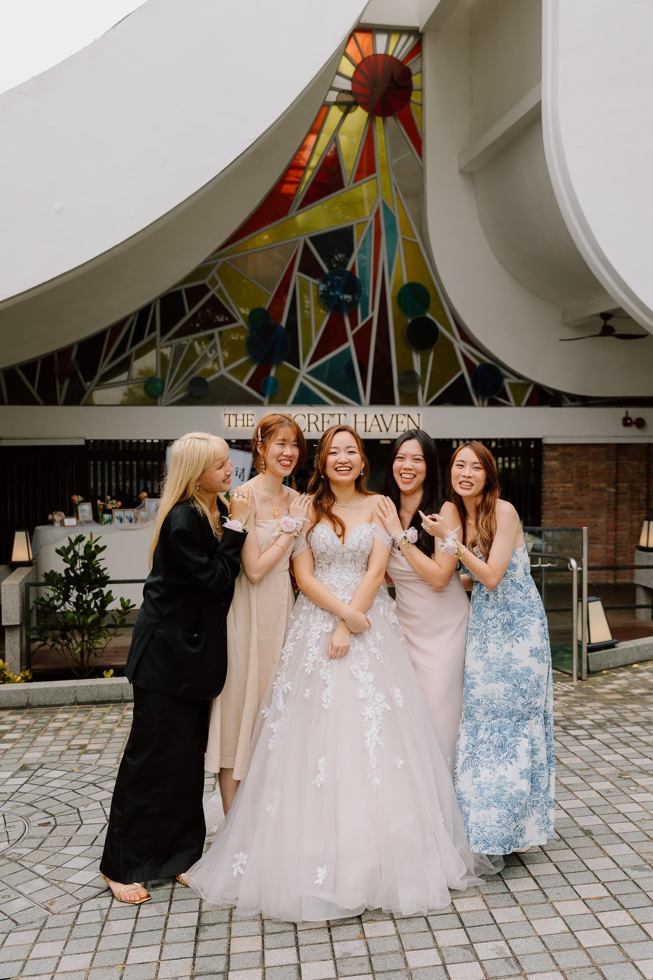 Bridesmaids in pastel dresses sharing a joyful moment with bride.