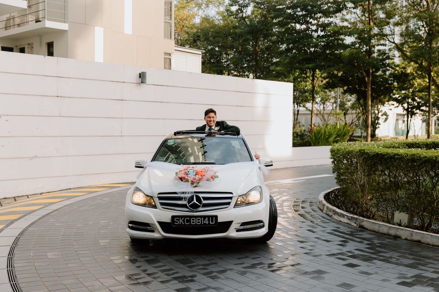 White wedding cars parked in sequence on a curved driveway outside a modern building.