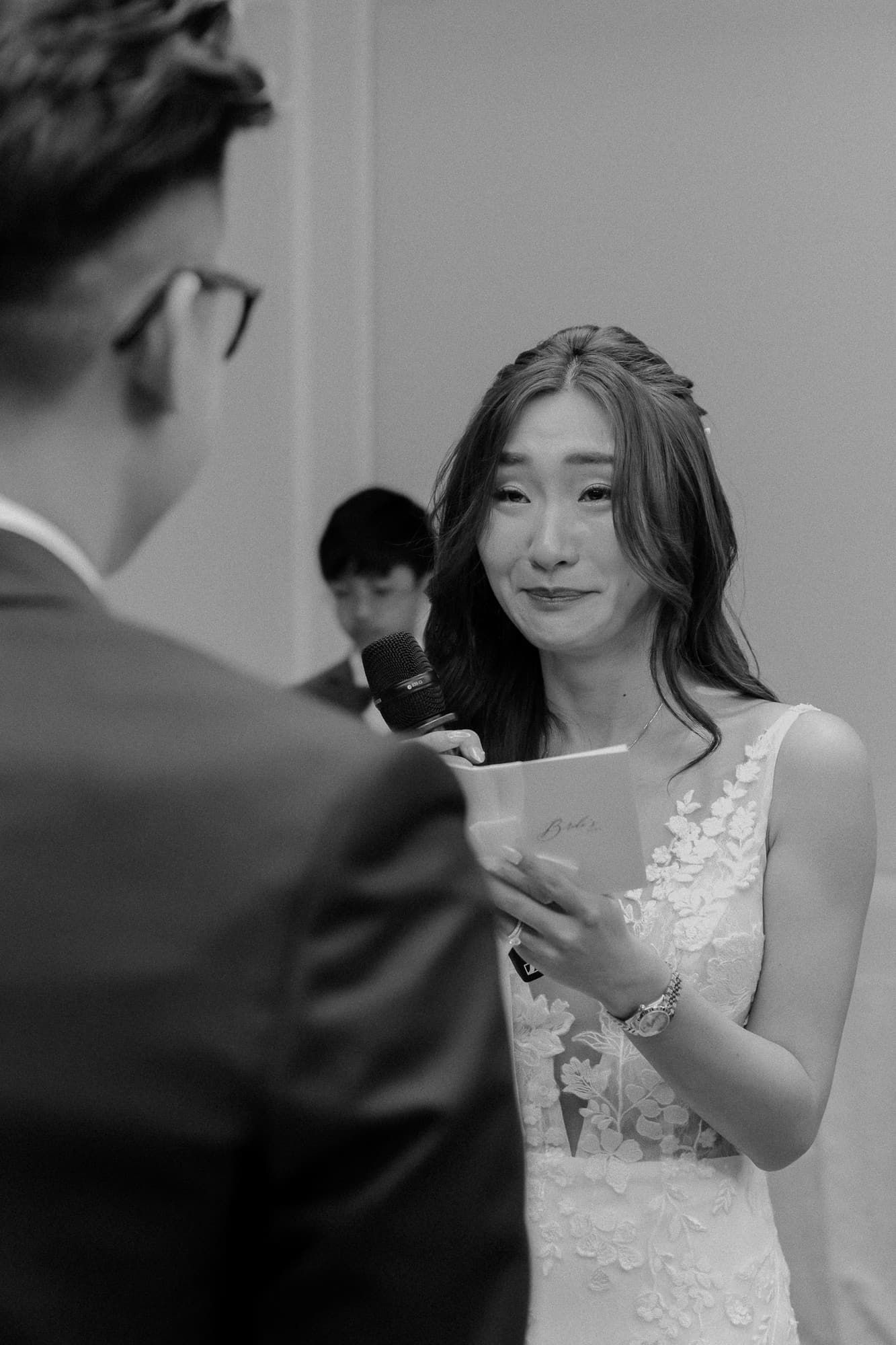 Black and white photo captures emotional exchange during wedding ceremony.