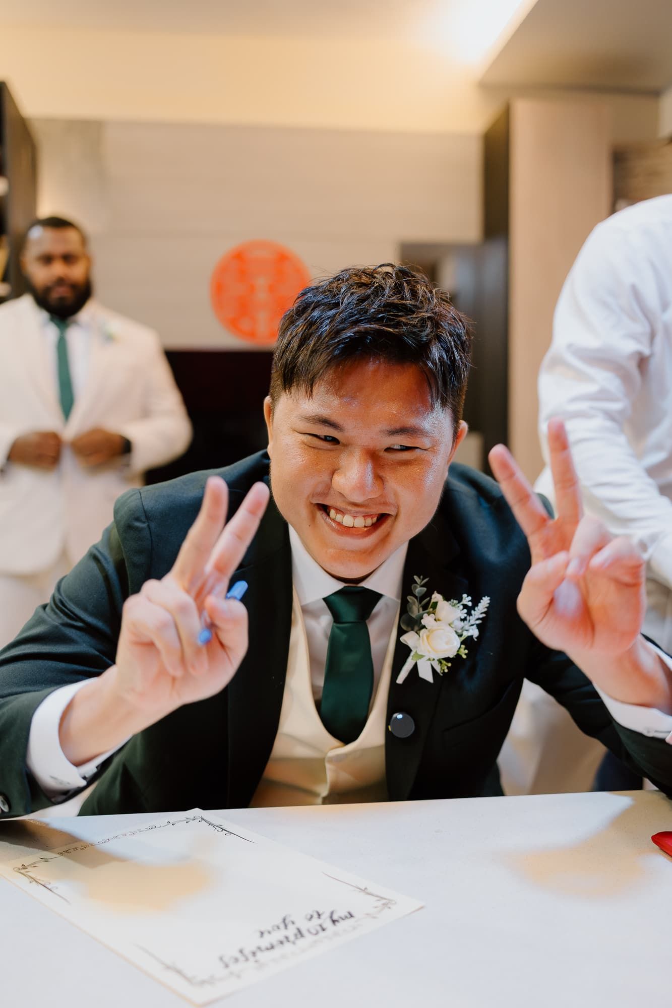 Cheerful wedding party members make peace signs while posing at a table.